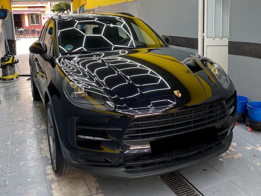 Black Porsche Macan at our car wash with the hexagonal ceiling reflected on the bonnet